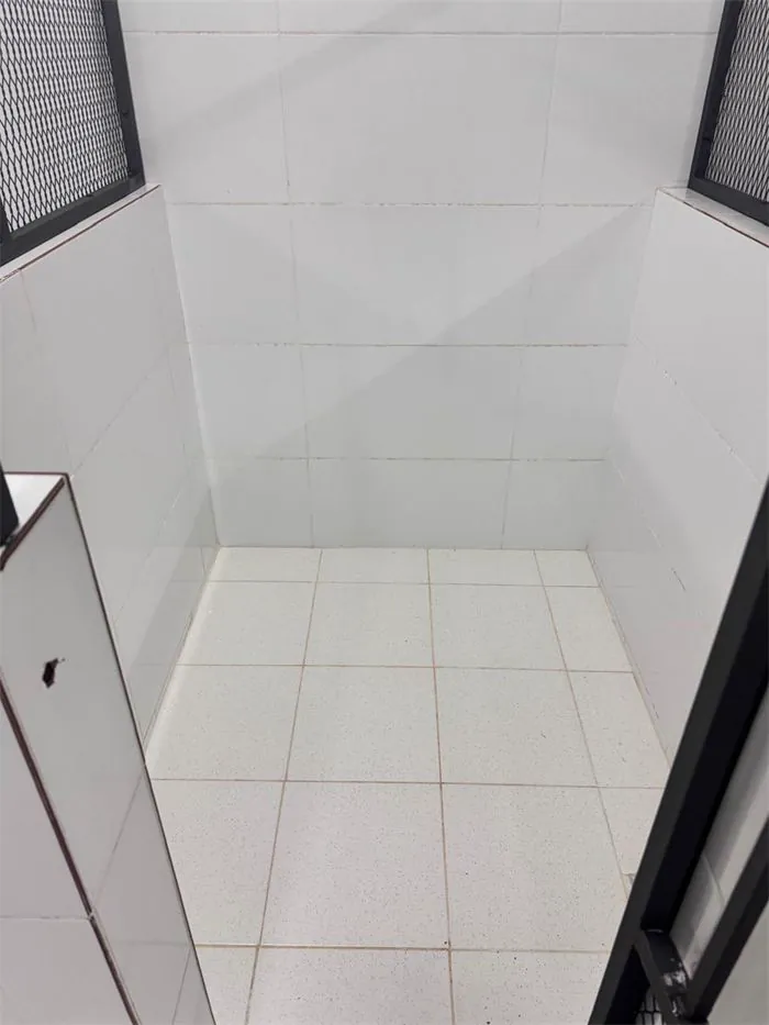 El interior de una habitación individual, con azulejos blancos